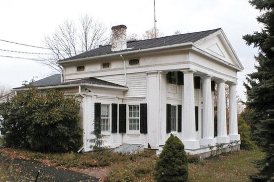 Repairing the colonnade involved rebuilding the porch, replacing rotted sections at the bottom of the non-structural columns, and eliminating makeshift plywood plinths that had been added in an earlier repair attempt. 