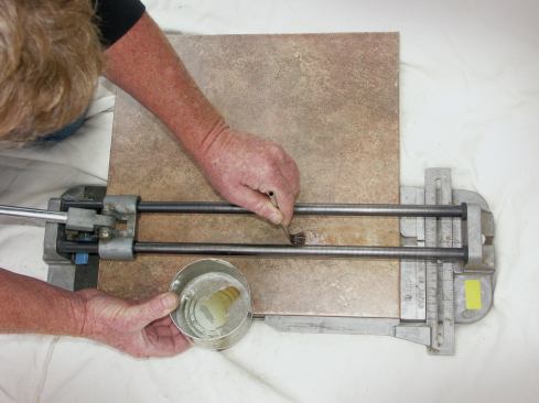 SCORE-AND-SNAP CUTTER 

Power tools are not always necessary, especially when making straight cuts in porcelain tiles. Because this dense tile is difficult to cut with a traditional score-and-snap cutter, many installers switch to a wet saw. But cutting porcelain can be slow even with a specialty blade mounted on the wet saw. Plus, the material has to be completely dry before it can be installed. The extra time that this entails can really eat into an installer’s profit. 

With the right technique, the lowly snap cutter can produce clean cuts in porcelain tile with little or no breakage. Before scoring the tile, brush the scoring path with kerosene or very light oil (26), then score and snap. The oil lubricates the scoring wheel for a consistent and even score, so all that’s left is to wipe off the residual kerosene or oil.