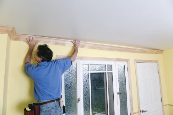 When working solo, the author uses his crown hook to support one end of the molding.