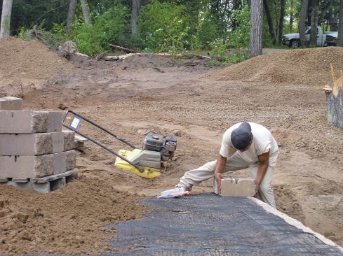 The geogrid reinforces the soil mass behind the wall and helps anchor the block courses in place.