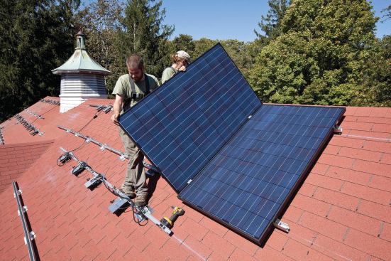 Starting at one end of the mounting rails, workers move modules into position and connect their positive and negative leads to the microinverter input fittings.