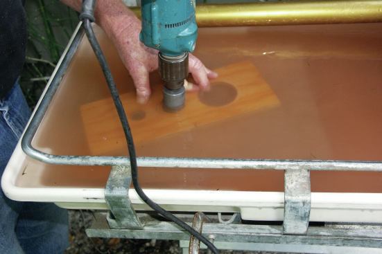 CUTTING HOLES IN TILE

Hole saws are traditionally the best tools for cutting standard-size holes in any material, and there are many diamond-edge hole saws on the market for cutting holes in tile. The problem with the ones I’ve used is that the carbide-tip pilot bit is absolutely useless — especially when I’m trying to get a clean hole in porcelain tile. So I remove the pilot bit completely. To prevent the hole-saw bit from wandering, I make a guide from a piece of scrap plywood with holes matched to the size of the diamond bit. 

Some diamond-core bits are advertised as dry-cutting — but even a dry bit can also be used with water. Bathing the tile and bit in water can extend the life of most bits 300% or more. To simplify wet cutting, I use a wet saw’s catch basin.

First, to avoid damaging the basin, I place a piece of scrap 3/4-inch plywood in the bottom. Then I mark the holes’ location on the face of the tile with an indelible pen. Next, I place the tile on the plywood shield and line up the plywood guide (23), making sure that the whole setup is under water. While pressing firmly down against the guide, I ease the bit into the face of the tile.

One complication is that the plywood guide inhibits the free flow of clean water. Therefore, I remove the plywood guide as soon as the bit creates a continuous circular kerf in the tile (24). This kerf will guide the bit the rest of the way through the tile. 