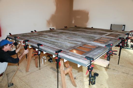 Then the carriage doors are clamped in place. Dozens of 3-inch self-tapping coated screws driven through the backs of the roll-up panels into the stiles and rails of the carriage doors join the wood and steel door sections together.