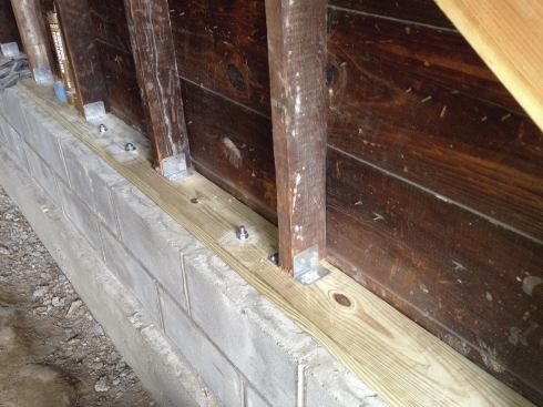 A pair of Simpson A23Z clip angles on each stud connected the wall to the mudsill, which was connected to the block with wedge anchors placed 2 feet on center.