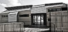 A traditional dog-trot porch separates the kitchen, on the right, from the living room and bedroom areas. The eccentric roof line is a stylized tribute to the vernacular “shotgun” house form.