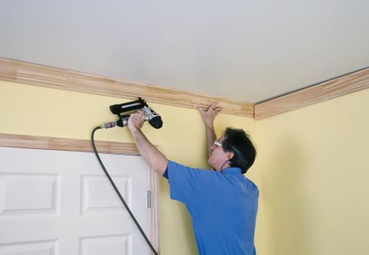 He slips the last piece in behind the coped end of the first piece and nails it off.