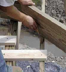 Figure 4. The cantilevered joists are purposely run long. The band board, aligned with the main deck, is placed atop the joists, which are then marked to be cut to length. Cleats nailed to the joists prevent them from moving and help to ensure accurate layout.