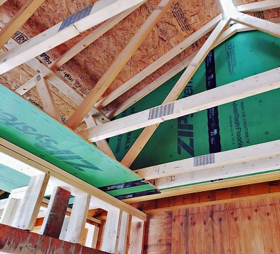 A variation on the theme: Here, 7/16-inch ZipSystem OSB is used as a portico ceiling outside, and is extended across the top wall plates. Inside the ZipSystem aligns with the ceiling drywall (to come). Also note the ZipSystem shathing, which separate, and seals, a second-floor living area from the open, vented attic in the foreground - a critical detail to ensure a continuous air barrier.