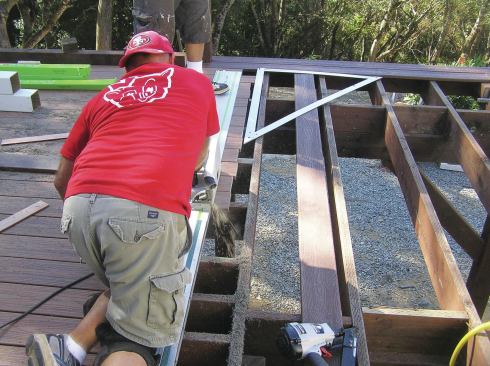 Trimming deck boards generates a large amount of sawdust. The dust-collection port isn’t connected to a vacuum here, but if it were, the jobsite would remain virtually dust-free.