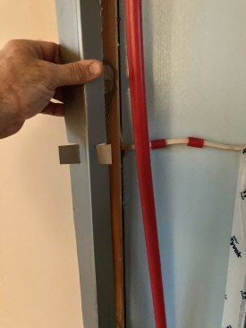 To protect the new supply runs, the author used half of a metal-framing track to create an angled piece of steel. Short pieces of PEX cushion an electric line that runs behind the pipes.