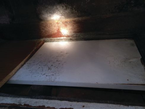 The main cold air return ran under the bay window, an area that was also used for storage. Note the moldy pressboard, which was soaked and falling apart.