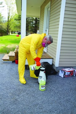 After gearing up with protective equipment, the author pours mold stain remover into a hand-pump sprayer.