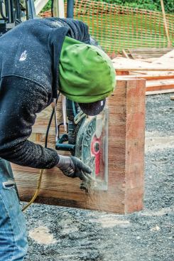 The maximum cut on a 10 1/4-inch saw is about 3 7/8 inches, so cutting through a 5 1/2-inch  glulam requires two cuts. With the beam positioned on edge and crown up on the forks of the forklift, Kyle Davis cuts vertically from one side ...