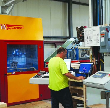 Brad Ramsey, the Hundegger CNC equipment operator, works the controls for the machine. Also at Ramsey’s fingertips is the control panel for the Joulin semi-automatic vacuum feeding system, which allows him to select and feed a variety of materials from a magazine into the cutting equipment.