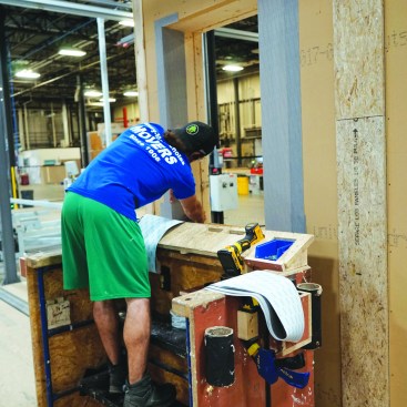 All doors and windows are detailed and installed before the walls are shipped, allowing the home to be blower-door tested as soon as the last panel is installed in the field. Greg Bruns preps the exterior of the rough opening for a window, using Siga tape.