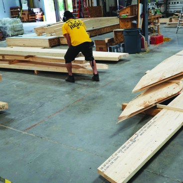All wall panels are fully airtight and watertight when they are shipped to the field. A worker manhandles parts for a custom curved roof package created by the Hundegger Speed Cut saw. The Unity Homes plant is capable of accomplishing fully panelized building shapes ranging from simple geometric forms to one-off architectdesigned creations.