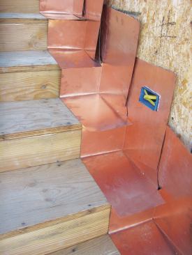 The copper stair flashing in the photo is just like deck flashing in miniature—when the cementitious deck coating is applied, it will completely cover the horizontal and vertical legs of the flashing.