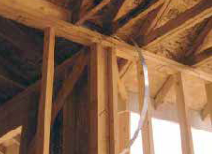 This strap, which runs from the top of a shear wall, will connect to the bottom of a roof truss above. Note that none of the trusses on the regular layout fell in line with the shear wall, so the builder had to add an extra offlayout truss to catch the strap. The roof sheathing will also have to be solidly nailed to this truss so that it picks up lateral forces in the roof diaphragm.