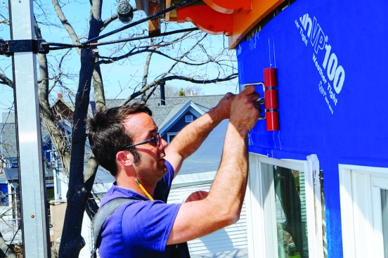 After covering the wall with Blueskin, he went over the whole area with a roller, a recommended practice that activates the material’s pressure-sensitive adhesive. He lapped the new Blueskin over the existing window flanges and frames, planning to cut the windows free one by one as he replaced them in a later step.