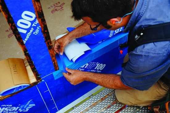 Each rough opening received a watertight wrap. After cutting and folding the membrane at the bottom of the curved windowsill, Pollard applied a custom-cut “bow tie” to the corner.
