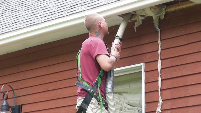 An Upright Frameworks worker installs dense-blown cellulose insulation into a rafter cavity through the soffit in a typical weatherizing retrofit.