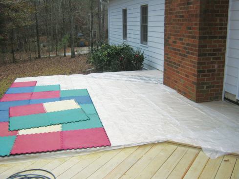 After installation, the author protects wood decking from rain and construction damage with a layer of plastic. The interlocking rubber mats provide additional impact protection and limit UV exposure.